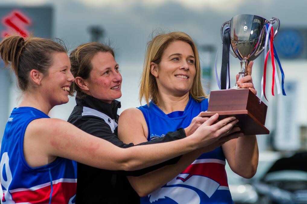 South Launceston's Emily Perkins and Abbi Dean surround Scottsdale's Letitia Johnston as they hold the premiership cup. Picture: Phillip Biggs.
