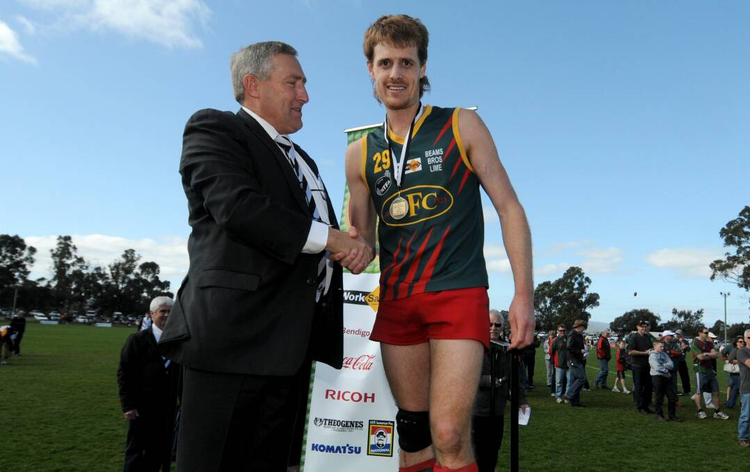 HIGH HONOURS: Jarrad Cirkel accepts the best on ground medal in the 2012 reserves grand final from then NTFA president Geoff Lyons.