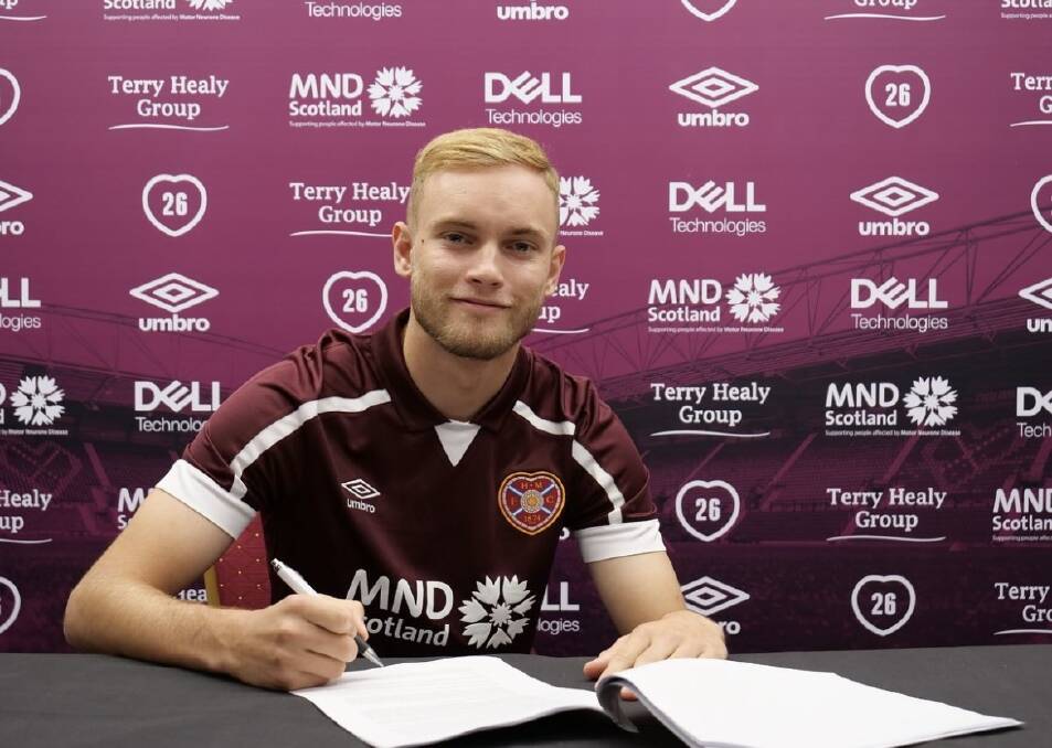 NEW COLOURS: Nathaniel Atkinson signs his contract for Scottish side Heart of Midlothian. Picture: Instagram