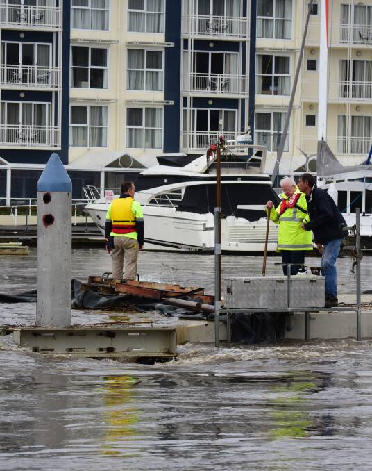 Errol Stewart (yellow safety top, second from right) and workmen inspect the pontoon at the North Esk Rowing Club.