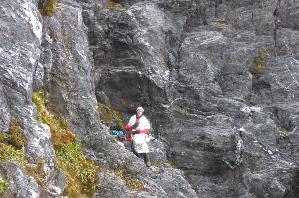 Ed Bastick perched on a cliff, waiting for the rescue helicopter