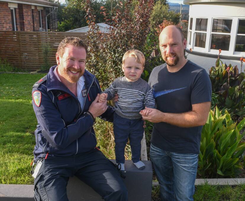 QUICK THINKING: Ambulance Tasmania paramedic Jared Baker with neighbour Luke Davis and his son Liam..Picture: Paul Scambler