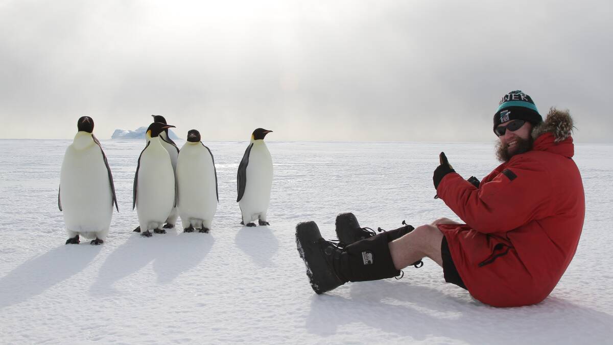 REMOTE ENVIRONMENT: Lincoln Mainsbridge enjoys some downtime with a group of emporer penguins while working in Antarctica. Picture: Supplied 