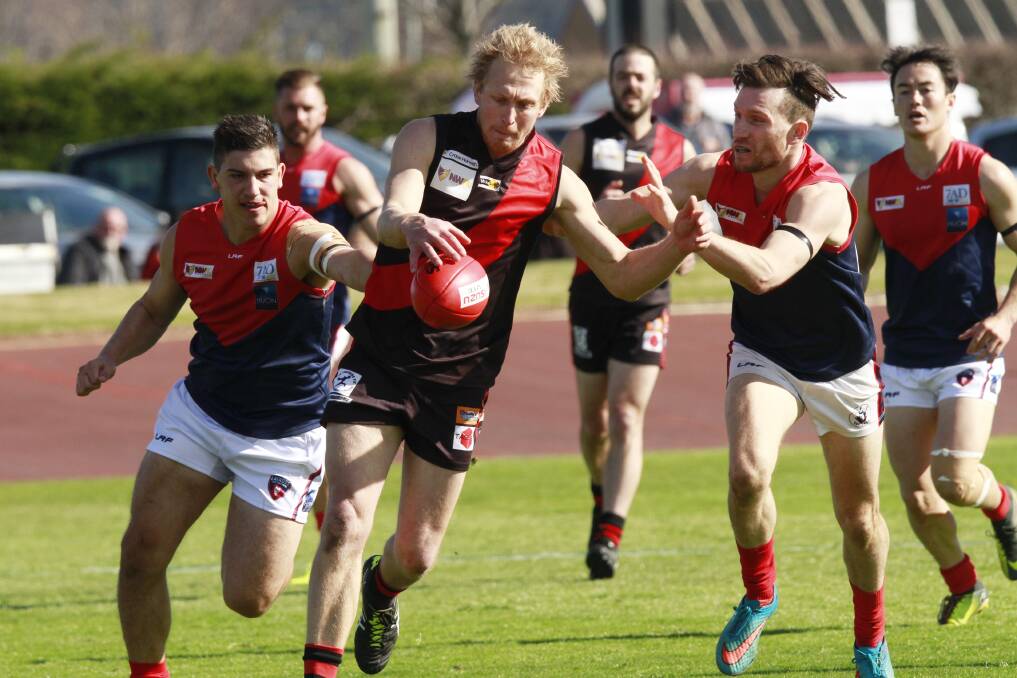 In time: Ulverstone's Jayden Marshall gets his kick away despite the best efforts of Latrobe's Brodie Deverell (left) and Shaun McCrossen (right). Picture: Brodie Weeding.