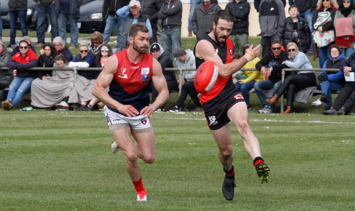 In time: Ulverstone's Tim Mee gets his kick away as Latrobe's Alex Baldock moves in to spoil. Picture: Brad Cole.