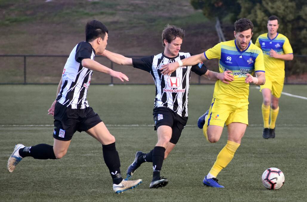 Devonport's Joel Stone tries to get past two Hobart Zebras' players in Sunday's match at KGV. Picture: Walter Pless.