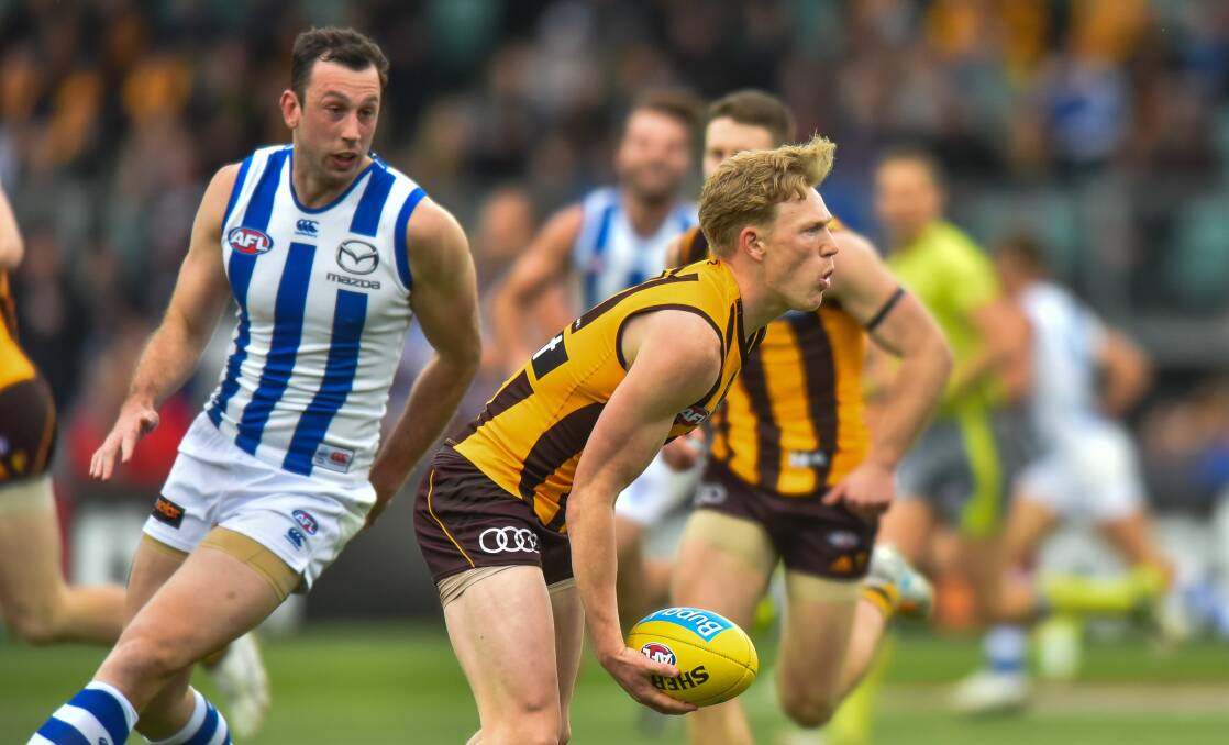 TASSIE TENANTS: Hawk James Sicily gets a handball away from Kangaroos ruckman Todd Goldstein. The two sides seem unlikely to fulfil their state contracts this year.