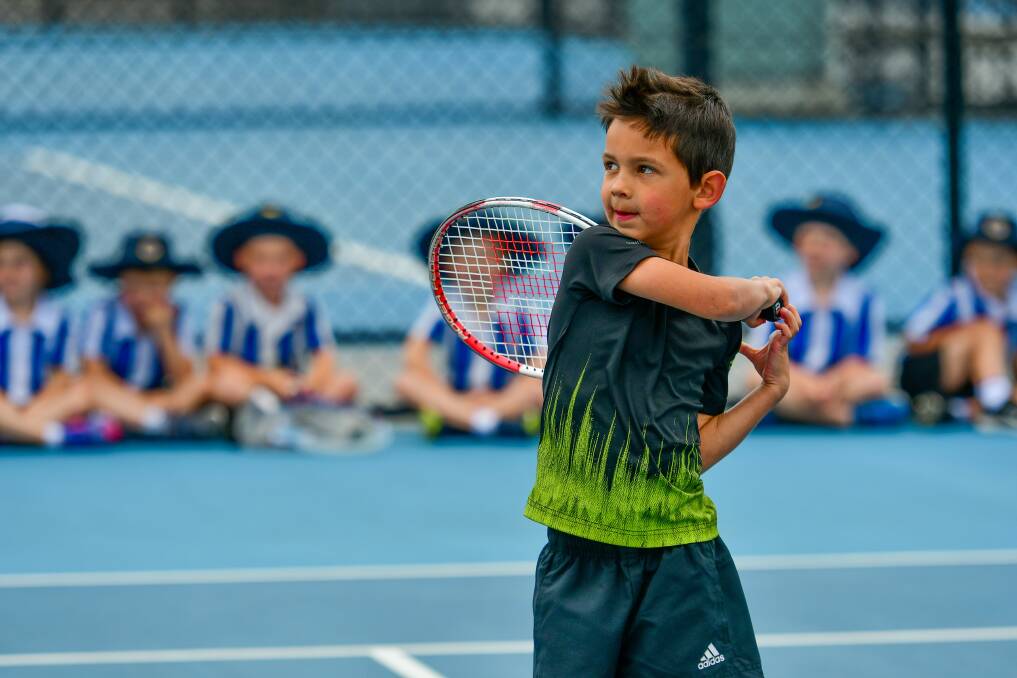 LOOKING UP: Beaconsfield five-year-old Chase Richardson practises his groundstrokes as his Grammar schoolmates cheer from the sidelines. Picture: Scott Gelston 
