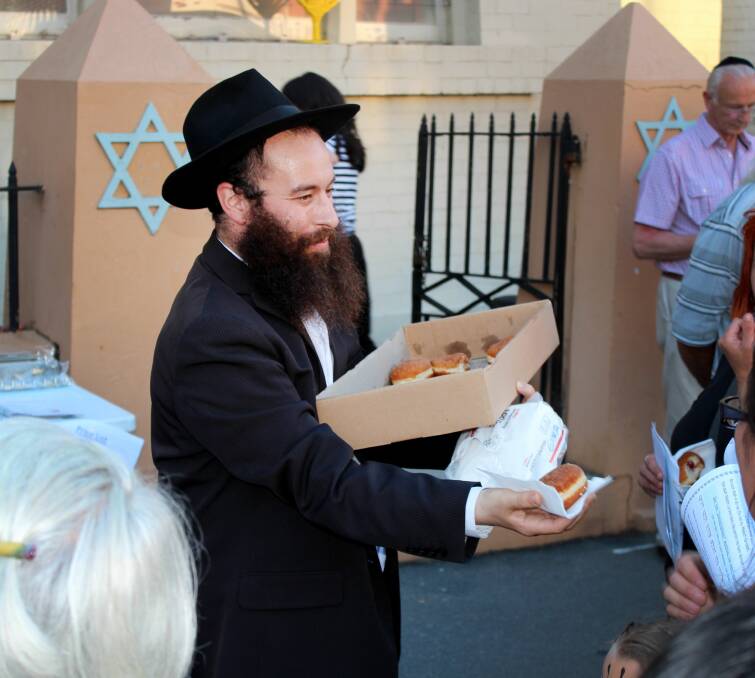NIGHT OF LIGHTS: Rabbi Yochanan Gordon hands out donuts at Chabad Tasmania's Chanukah celebrations in St John Street. Picture: Hamish Geale 