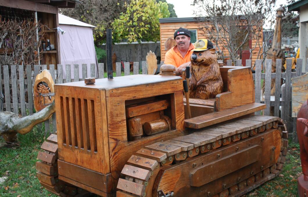 TIMBER TRACKS: Ross chainsaw carver Eddie Freeman shows off his pine de resistance, a life-size bulldozer with moving parts, ahead of the Campbell Town show. Picture: Supplied