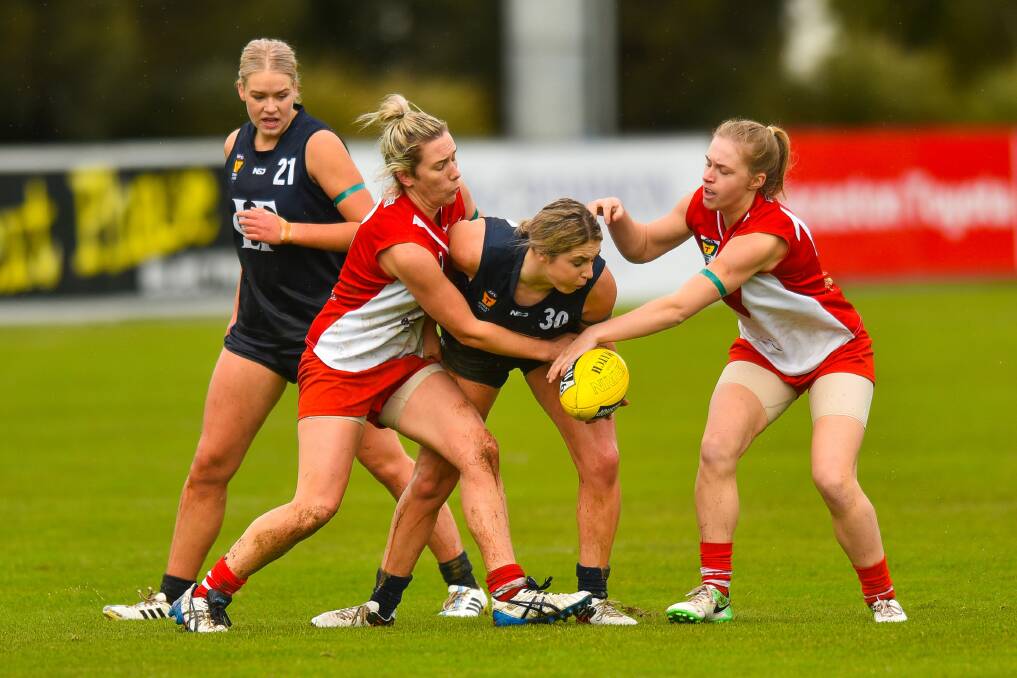 SKIPPY: Launceston's Molly Clark gets wrapped up in a Roo sandwich. Clarence and the Blues will fight it out for a grand final berth in the state's South on Sunday. 