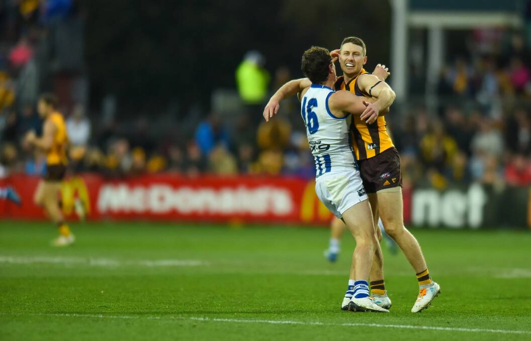 TOO CLOSE FOR COMFORT: Hawthorn midfielder Liam Shiels in the arms of a North Melbourne opponent.