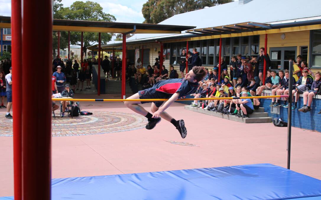 UP AND OVER: High jumper Liam Johnson enjoys the support of his schoolmates. Pictures: Supplied