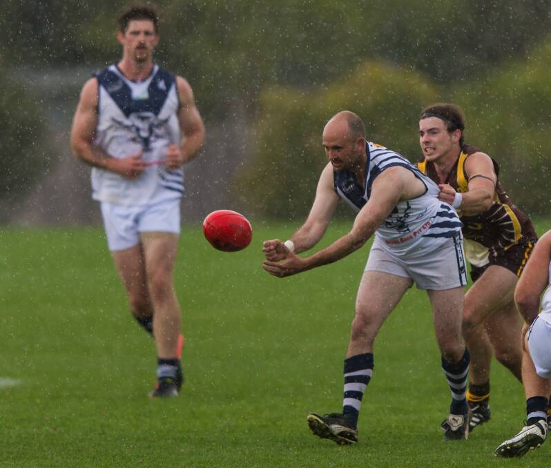 SLIPPERY CONDITIONS: Tamar Cats' Bryan Tasker gets a handball away. The Cats will set their sights on Meander Valley this weekend. 