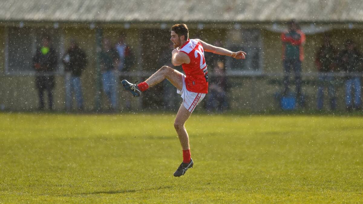 SUN SHOWER: Bracknell's Brodie Stokell boots it forward as rain falls during the match against Bridgenorth. The Redlegs won by 10 goals to go equal top. Picture: Scott Gelston