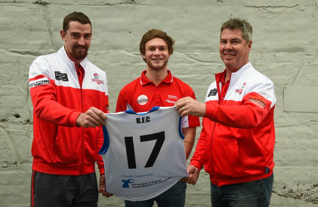 REDLEGS IN BLUE: Bracknell 200-gamer Craig Burling, vice-captain Jack Dyer and assistant coach Andrew Philpott inspect their one-off guernsey. Picture: Paul Scambler 
