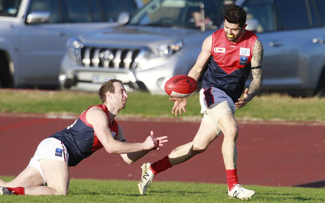 TEAM WORK: Latrobe's Josh Newson gets a diving handball away to Liam Burley late in the game on Saturday as the Demons destroyed Devonport. Picture: Brodie Weeding. 