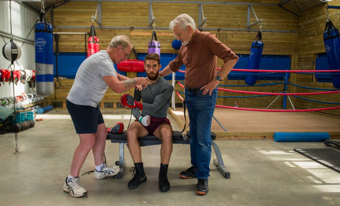 READY: Tasmanian boxer Jack Unwin prepares for his professional boxing debut as coach Graeme George laces his gloves and former Olympian Wayne Devin watches on. Picture: Scott Gelston
