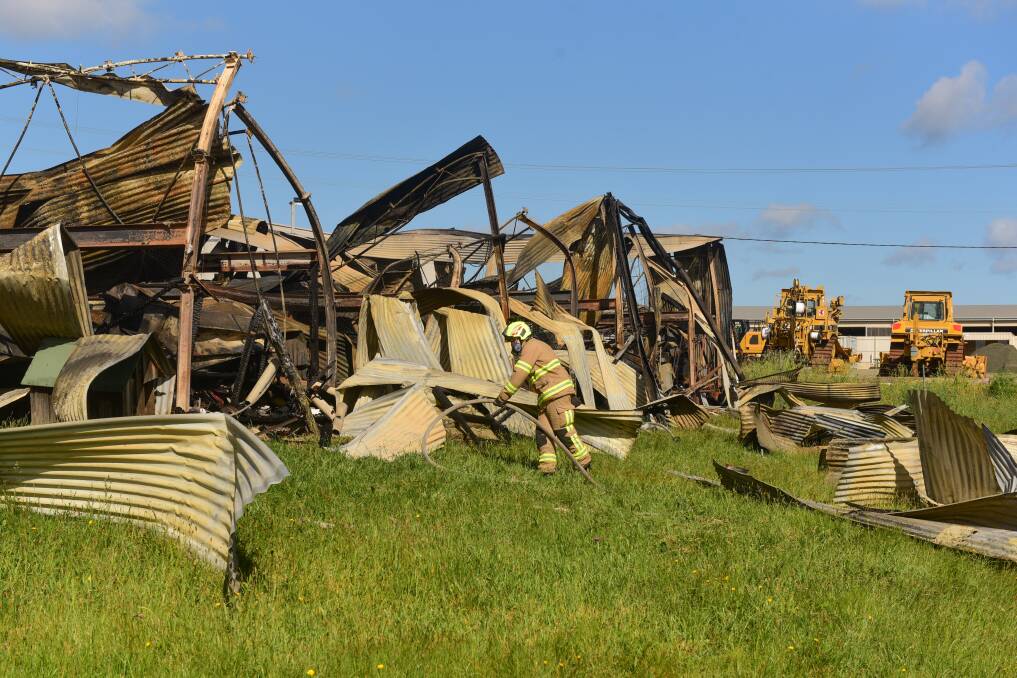 Wreckage: Fire crews work to dampen hot spots on the destroyed shed. Picture: Paul Scambler.