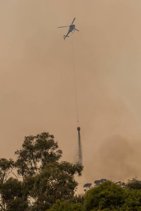 A helicopter drops water on a fire near Fingal on Sunday. Picture: Phillip Biggs