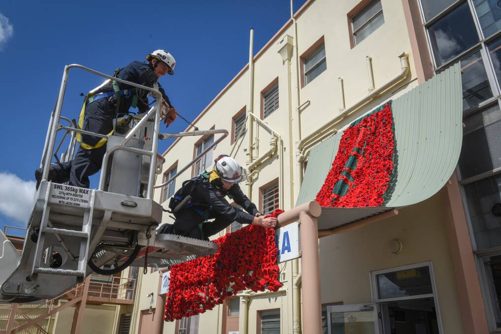 Senior firefighter Roger Brown and firefighter Simon Moore help the Launceston Womens Auxillary install their "poppy waterfall" at the Launceston RSL. Picture: Paul Scambler.