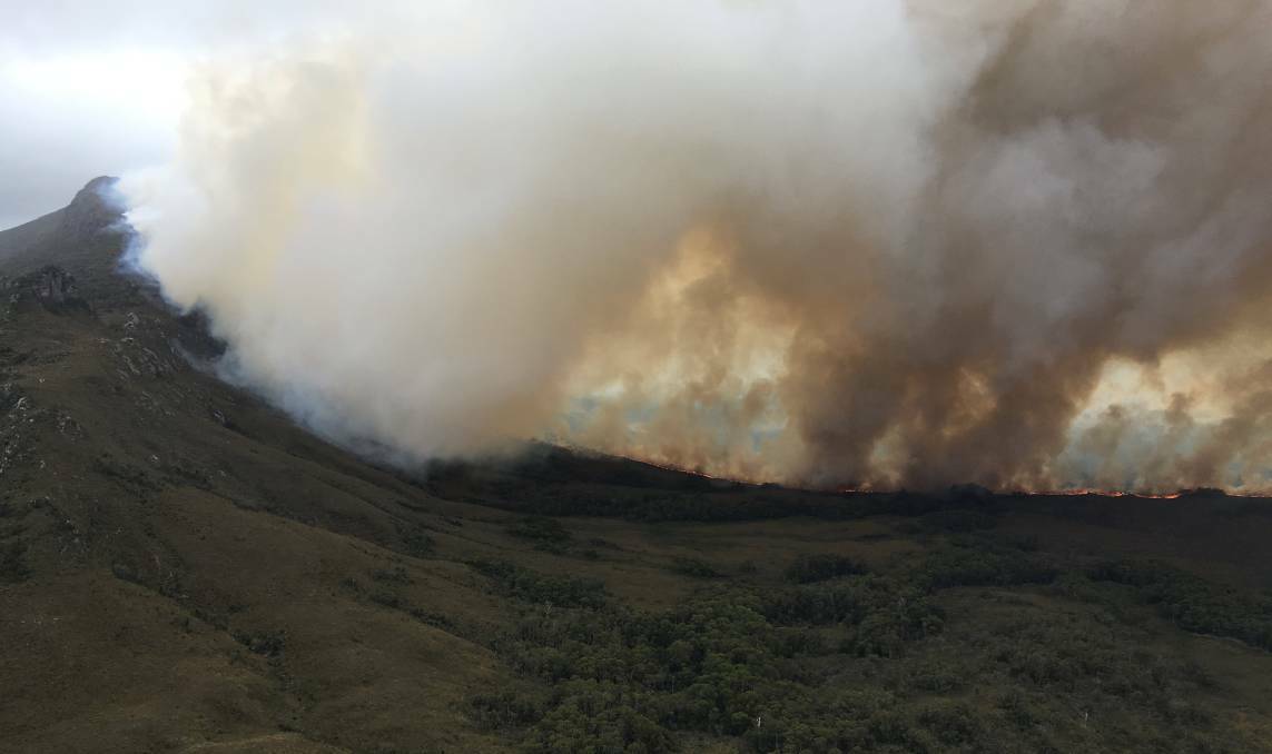 The Gell River bushfire burns towards Denison Range as firefighters form containment lines at the Gordon River. Image: NSW RFS