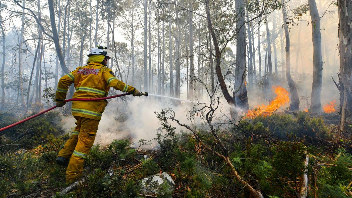 Dilston Fire Brigade's Adam Smith works to strengthen a containment line at Penstock Lagoon. Picture: Scott Gelston