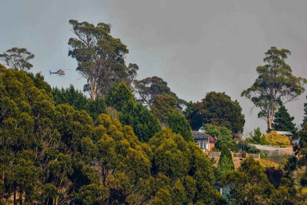 BATTLING: Helicopters fly over properties in Mason's Road. Advice level alerts for the Exeter blaze remained for a number of areas on Tuesday night. Picture: Scott Gelston