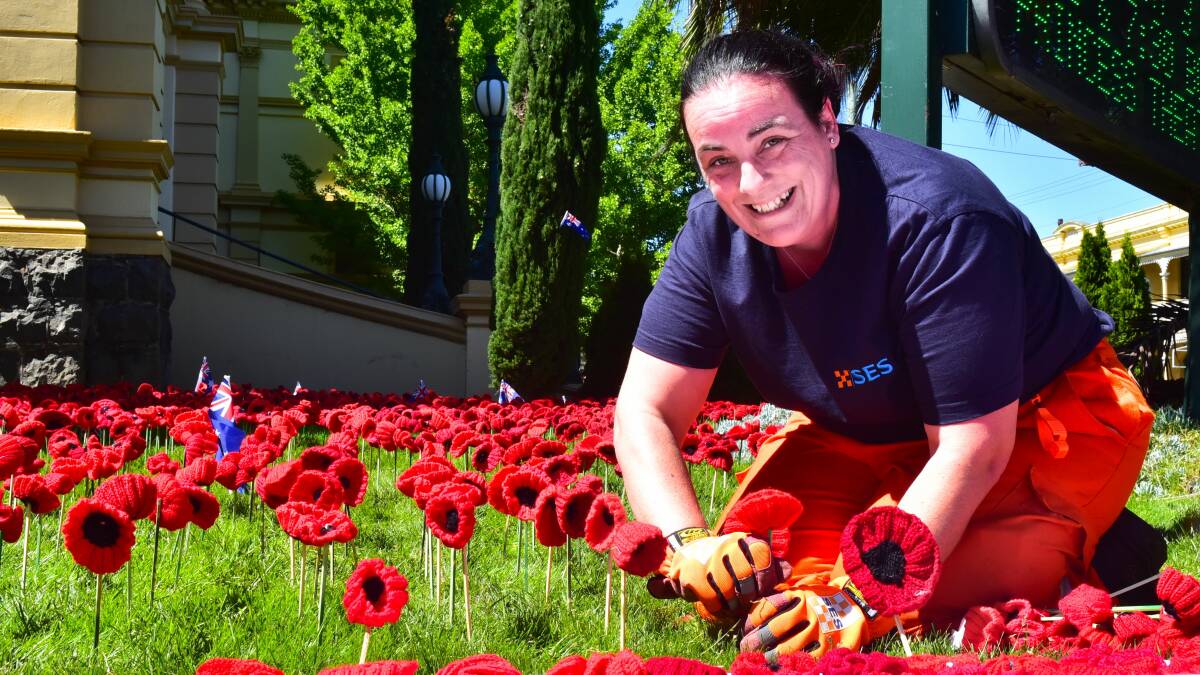 PREPARING: SES volunteer Sarah Clark plants the knitted poppy display at Albert Hall ahead of the Centenary of Armistice Remembrance Concert. Picture: Neil Richardson