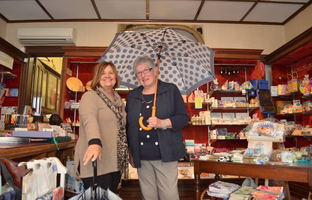 STAYING DRY: Noelene Burndred and Mary Lees volunteer at the Old Umbrella Shop in Launceston. Pictures: Tess Brunton