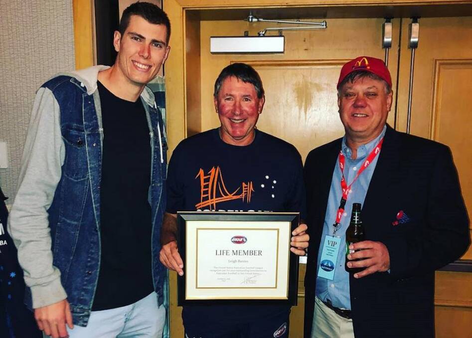 Collingwood's American star Mason Cox and USAFL founder Paul O'Keefe both present Leigh Barnes with its life membership of the Australian game in the US. Pictures: Supplied