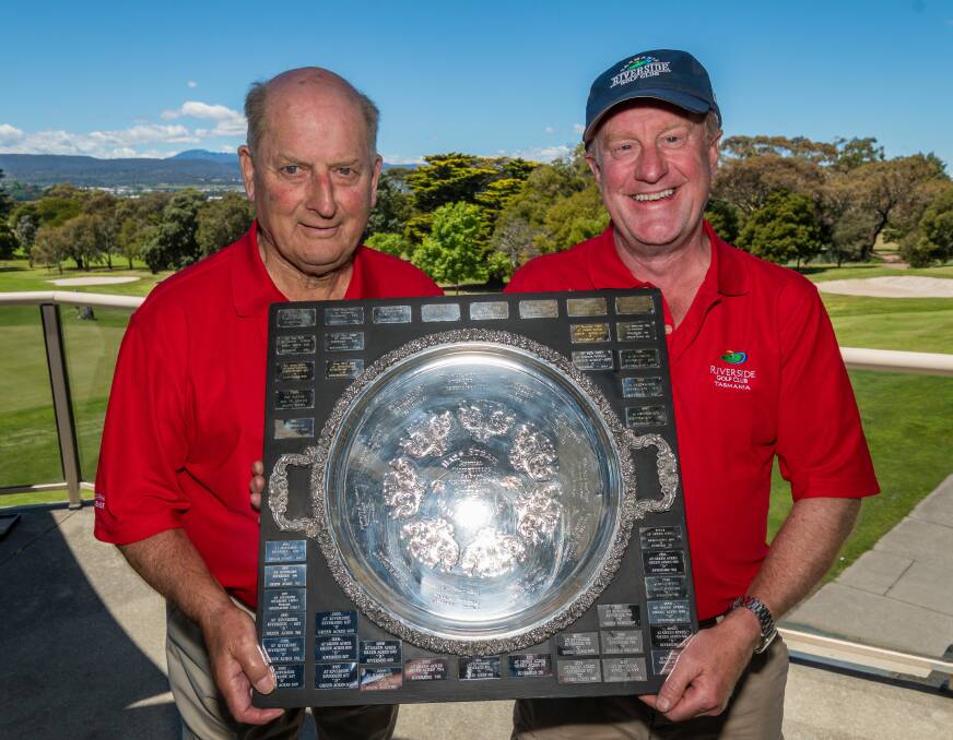 OLD HANDS: Peter Glover and Michael Guy hold up the traditional Bass Strait golfing trophy between Riverside and Green Acres clubs. Picture: Neil Richardson