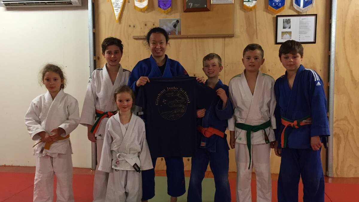 COMBATIVE: New Ginkan Judo School instructor and recent national champion Hanä Shimazaki embraces several of her enthusiastic students at the Sidmouth club. Picture: Supplied