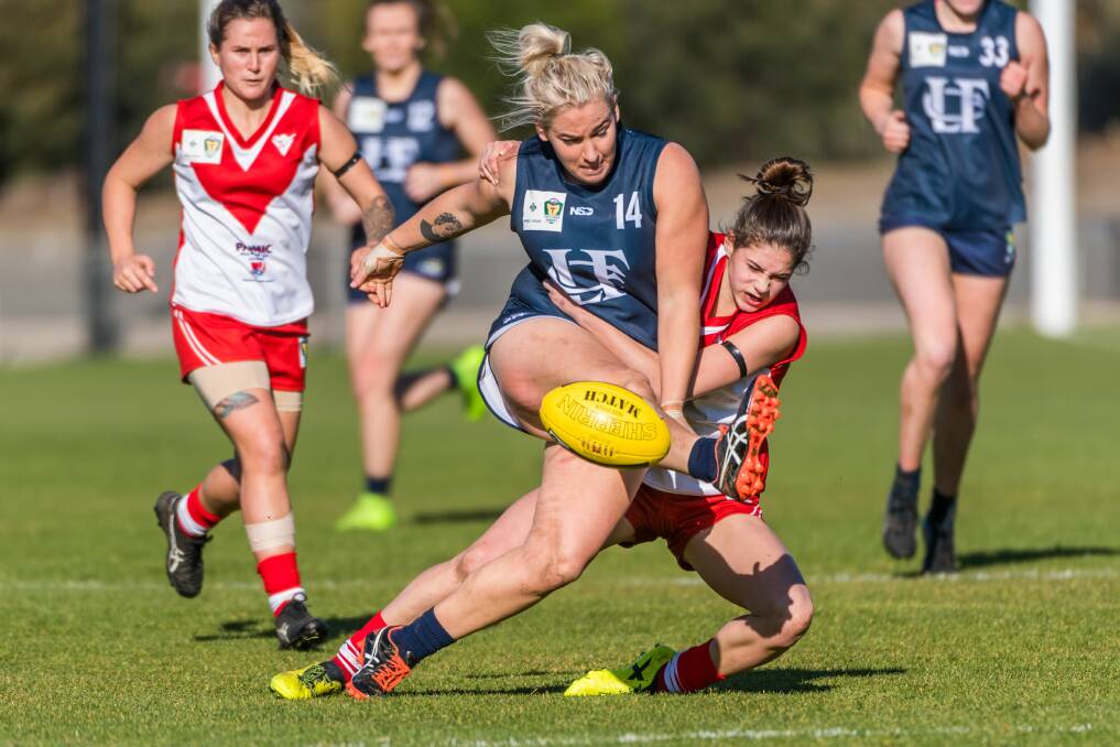 HARD YAKKA: Blues campaigner Ashlee Carey struggles to get boot to ball from the fierce work of Clarence tackler Tahlia Bortignon. 