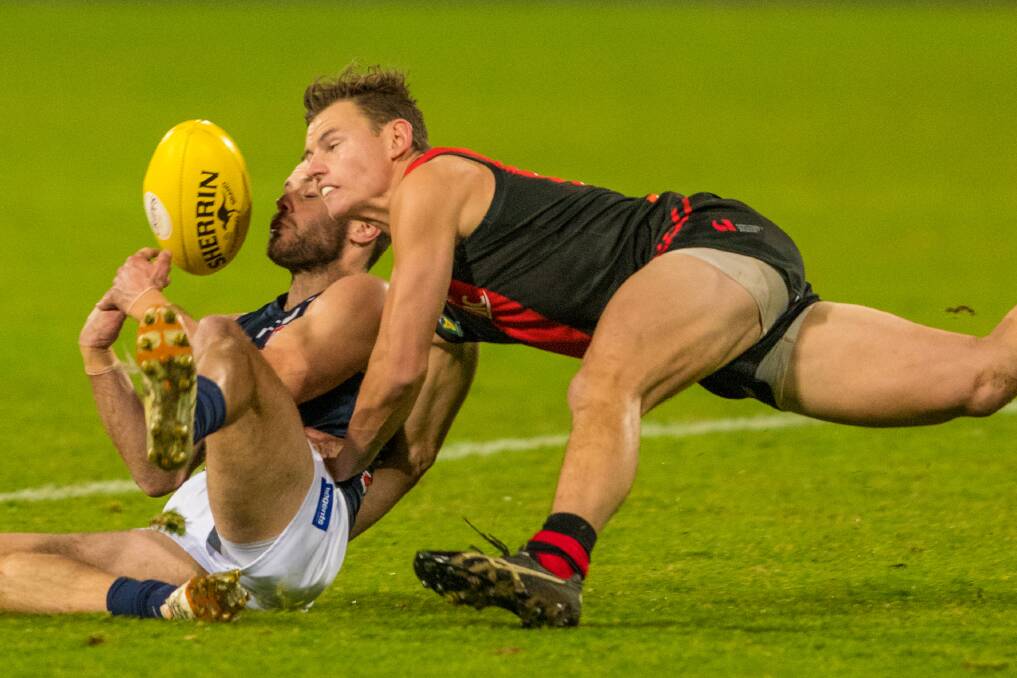 ON HIS KNEES: Launceston captain Jay Blackberry scavenges for a ground-ball mark against Bombers defender Jack Avent on Friday night at UTAS Stadium. Picture: Phillip Biggs