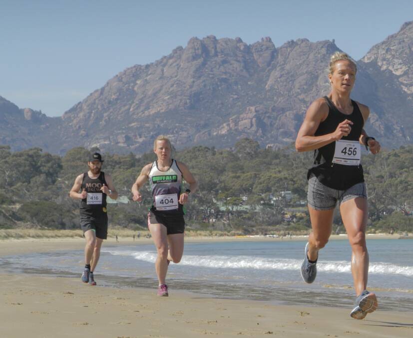 BEACH STROLL: Kate Pedley pushes ahead of Amy Lamprecht and Ben DeRue on the sands of Coles Bay during the run leg of the Freycinet Challenge on Sunday. Picture: Pete Harmsen
