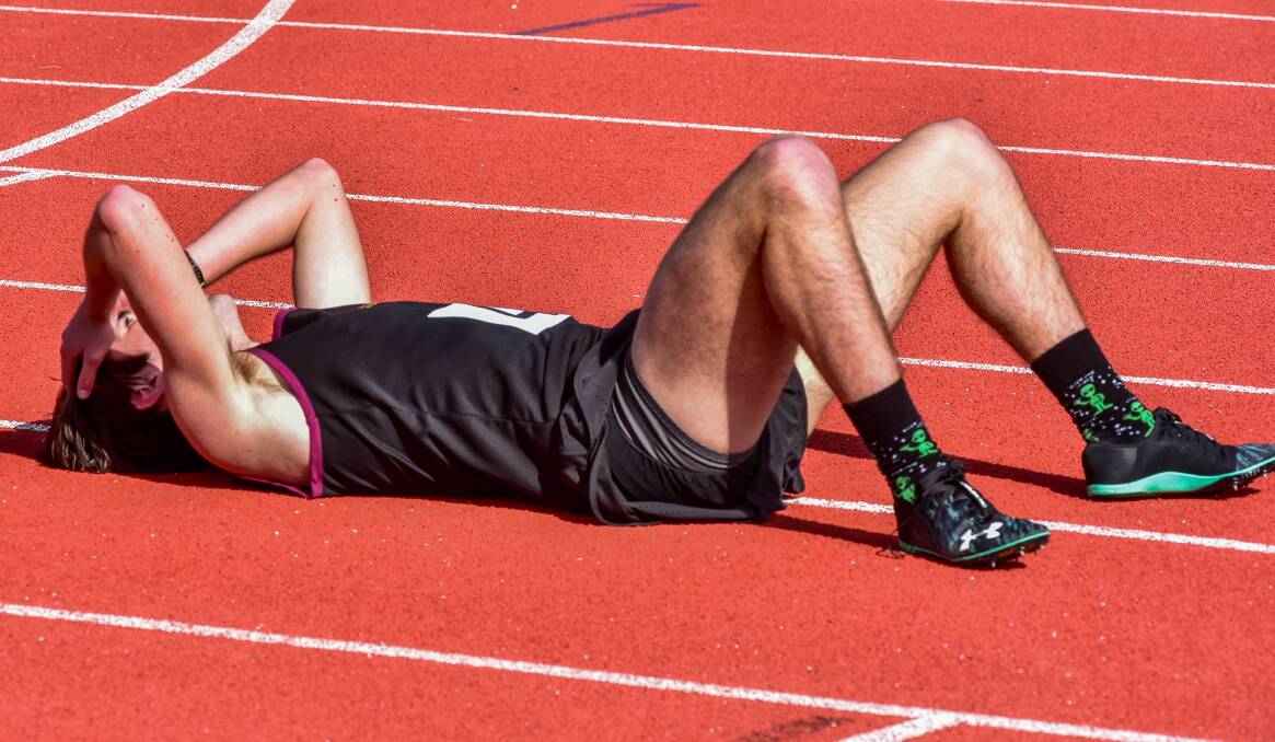 I'VE DONE IT: Hutchins School distance runner Harvey Chilcott lies on the track relieved for not only winning his 3000m race but for also breaking the Sports Association of Tasmanian Independent Schools' record at St Leonards on Saturday. Pictures: Neil Richardson