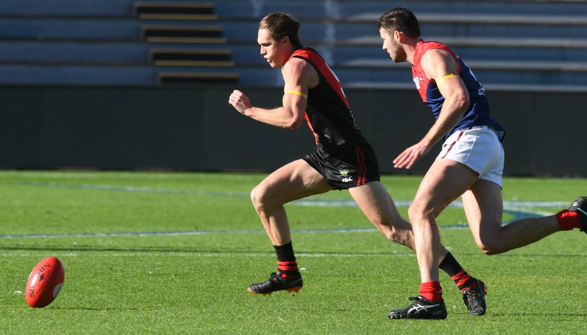 PACE: Former AFL Demon and North Hobart star Colin Garland gives chase to North Launceston defender Connor Young last time at UTAS Stadium.