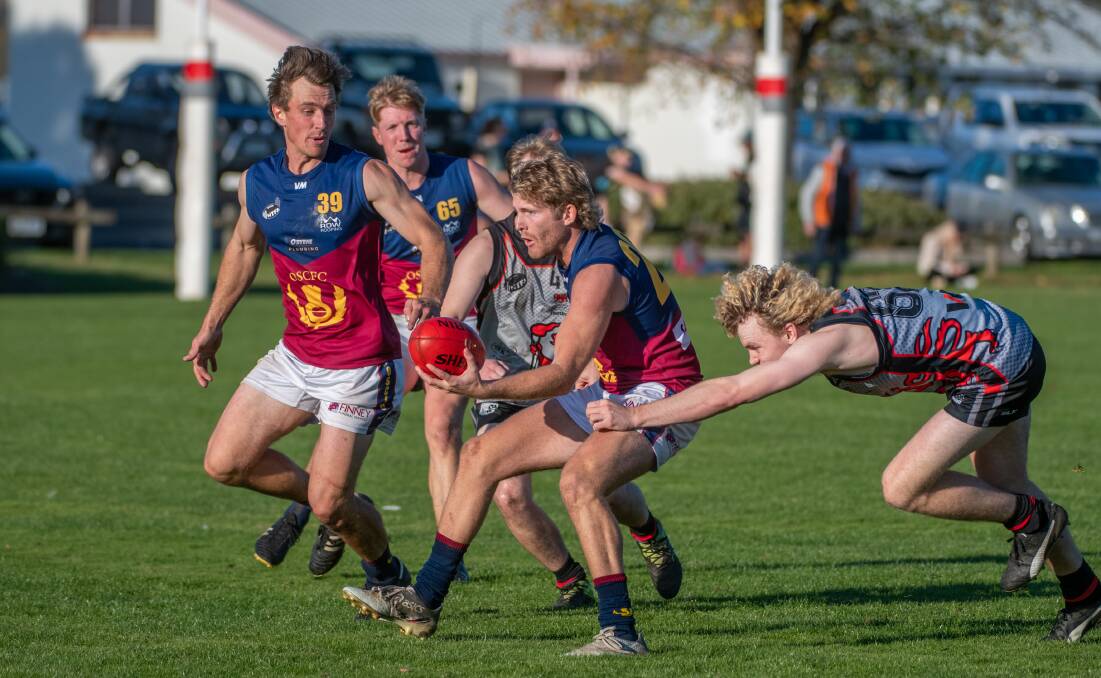 IN THICK OF ACTION: Old Scotch's Lachie Bremner dishes off under pressure from UTAS' Charlie Williams. 
