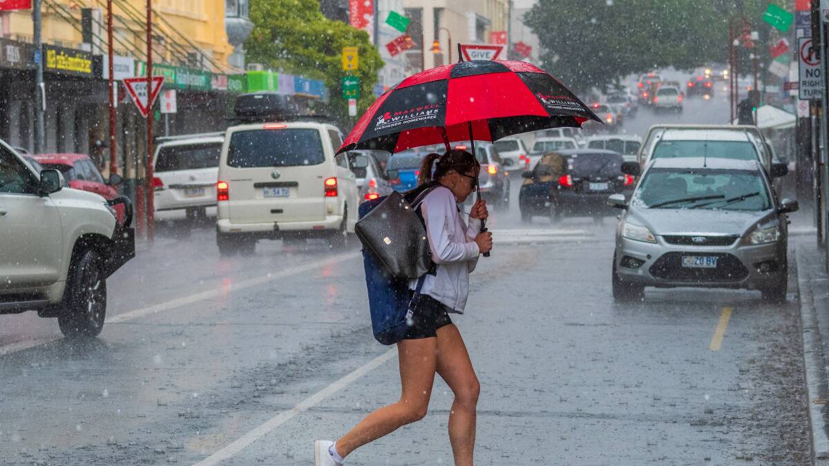 A woman takes cover under her umbrella. Picture: File