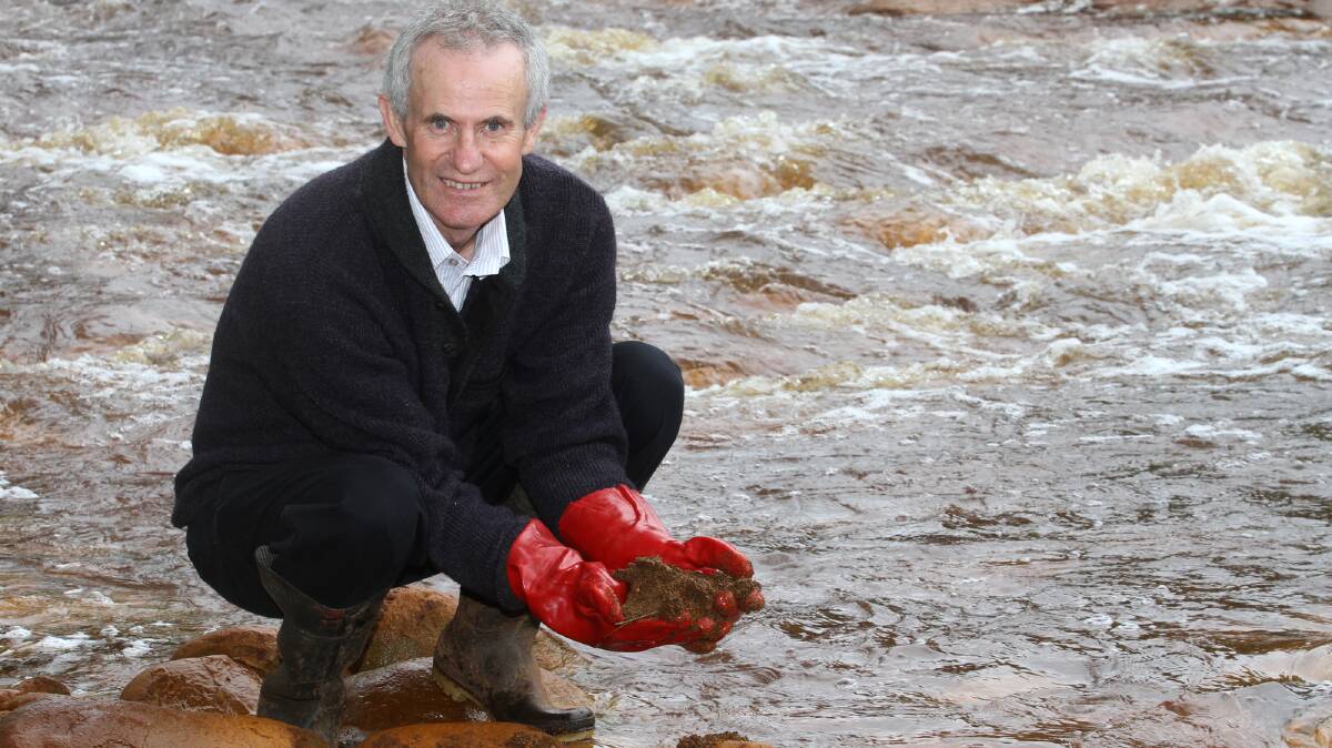 Former Greens MHA Paul O'Halloran with a handful of brown copper slime from the heavily polluted Queen River on the West Coast.