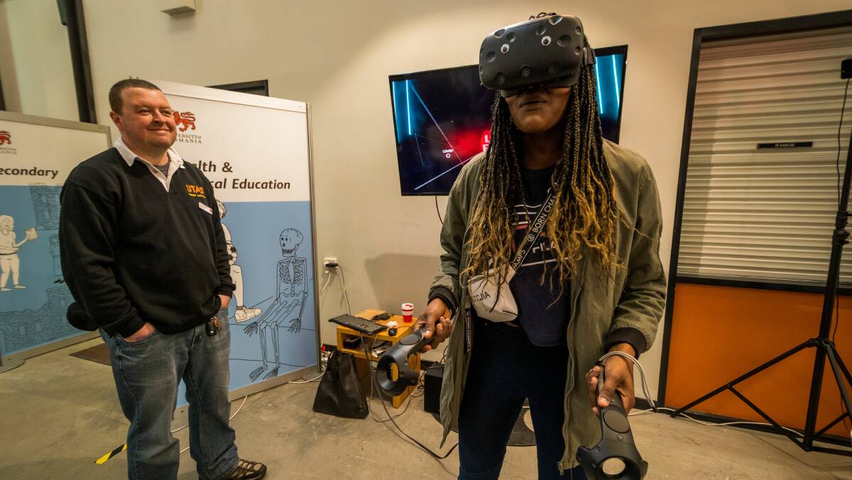 REALITY CHECK: Magdalia Koko, of Newnham, experiences an interactive 3D light sabre drum simulator exercise game, watched by Scott Pederson, of Active Work Laboratory. Picture: Phillip Biggs
