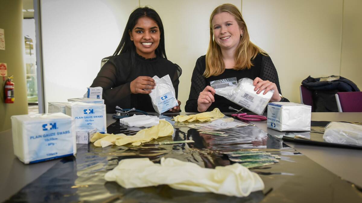 GOOD CAUSE: UTAS Launceston Clinical School fourth year medical students Dipti Sugumar and Georgia Roberts, help assemble birthing kits. Picture: Paul Scambler