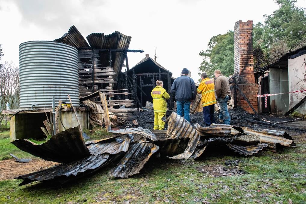 Fire investigators and owners of the Deloraine cottage inspect the damage on Tuesday. Pictures: Craig George 