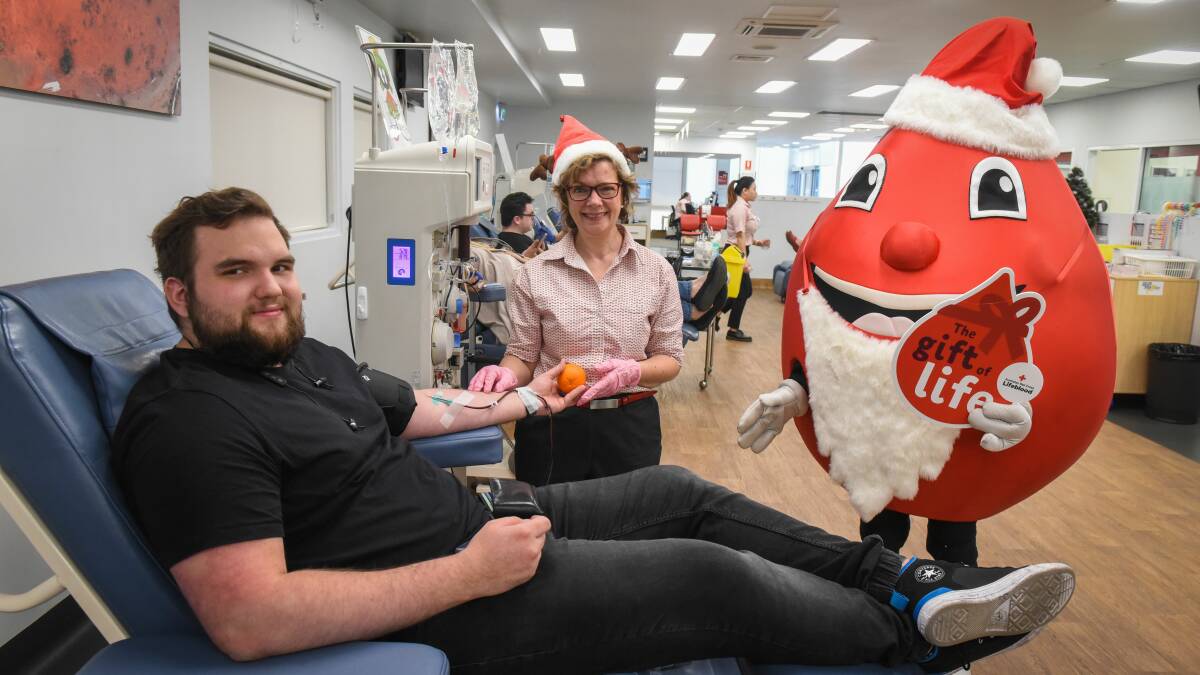 CARE: Matthew Beyer, of Launceston, donates blood as part of the Secret Santa exchange on Thursday, with Red Cross Lifeblood's Ann Harvey. Picture: Paul Scambler 