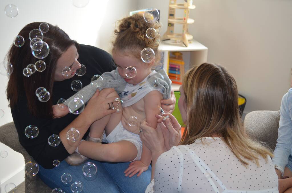 Amelia McFarlane, 3, of Trevallyn, receives her flu vaccination from Dr Jackie O'Keefe, with the help of mum Kat. Picture: Jessica Willard 
