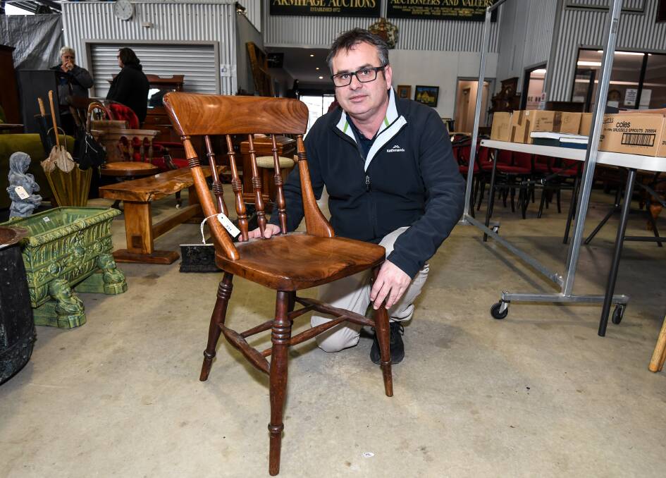 High Prices: Auctioneer Andrew Snooks with the chair sold at auction.