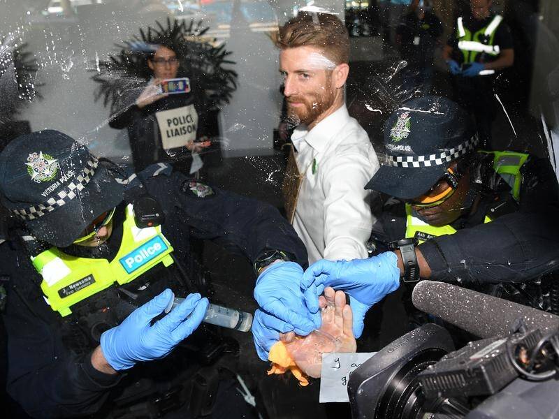 Police work to remove an Adani protester who glued his hand to the Siemens Melbourne office.