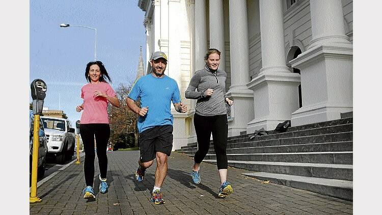 Wife and husband Kathryn and Martin Fox, with Sarah Guest, all of Launceston, run past the Town Hall in preparation for the Launceston Ten. Picture: PAUL SCAMBLER