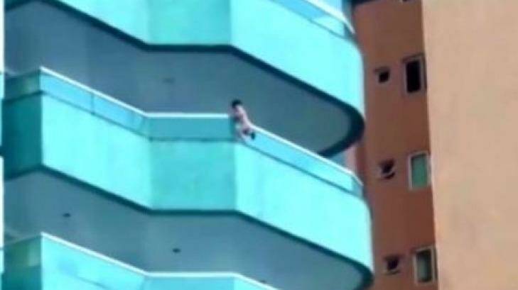 A toddler hangs from the balcony of a building in Brazil. Photo: Supplied